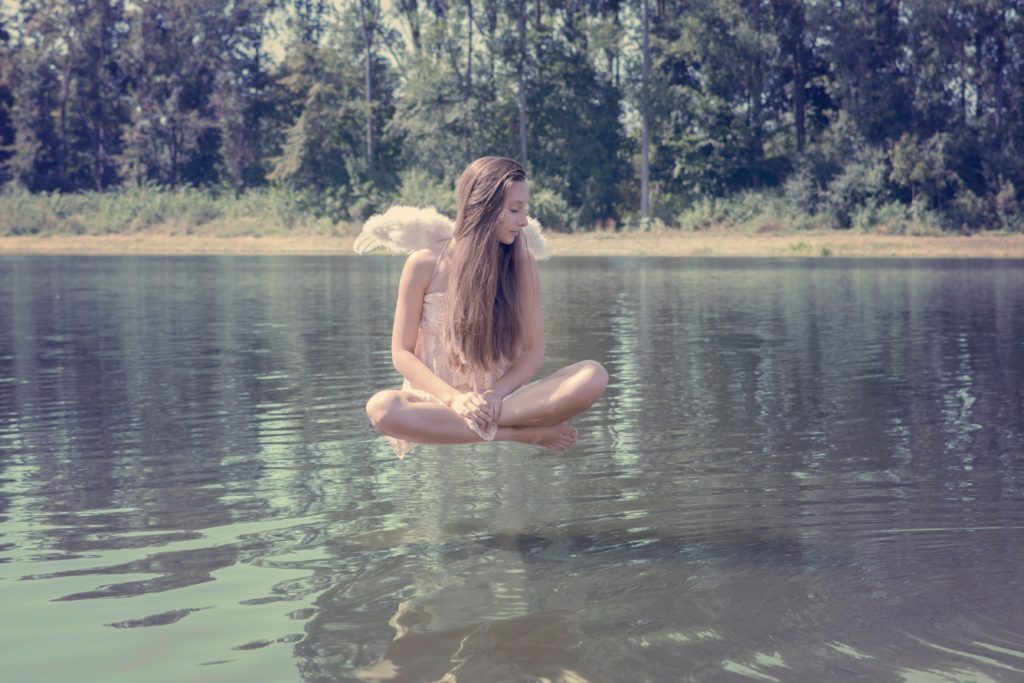 Ange feminin au flottant au dessus d'un lac