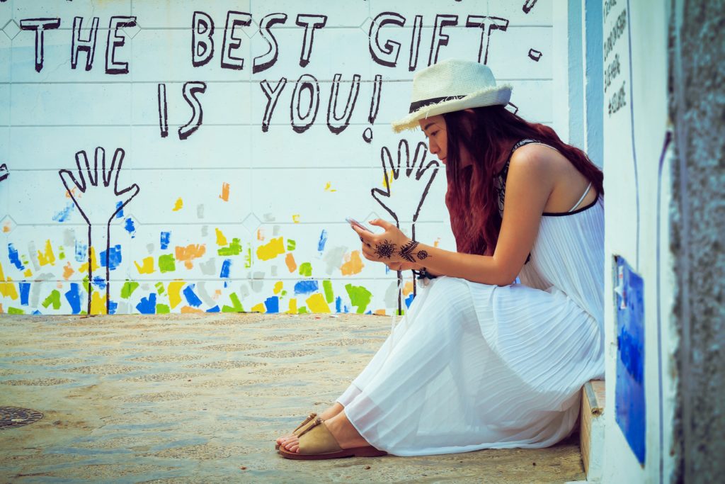 Femme assise sur une marche devant un mur blanc 